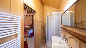 A wooden interior with a white sink, mirror, and shower.