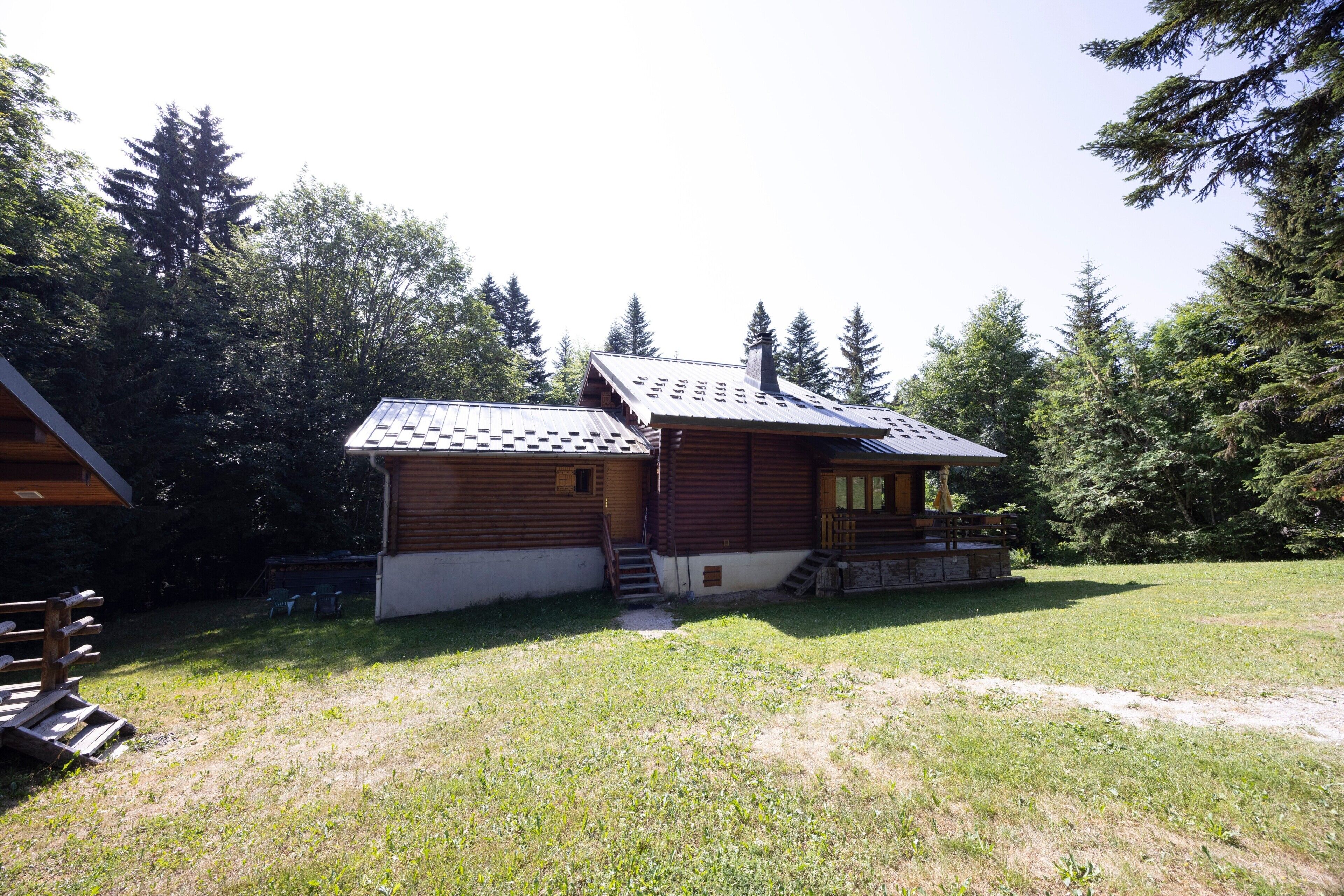 A wooden cabin with a sloped roof, a porch, and a small staircase leading to the entrance.