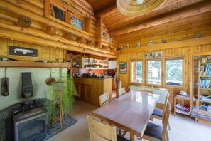 Ein Holzhütten-Interieur mit Essbereich, Küche und Kamin.