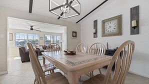A dining area with a wooden table and chairs, a chandelier, and a clock on the wall. - Gulf Access Getaway, 4 Kayaks, Dock, Fire Pit & Waterfront Fun, Boat Dock, FirePit, Bikes (Hernando Beach)