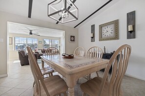 A dining area with a wooden table and chairs, a chandelier, and a clock on the wall. - Gulf Access Getaway, 4 Kayaks, Dock, Fire Pit & Waterfront Fun, Boat Dock, FirePit, Bikes (Hernando Beach)