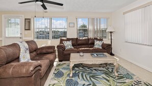 A living room with two brown leather sofas, a coffee table, a ceiling fan, and large windows with blinds. - Gulf Access Getaway, 4 Kayaks, Dock, Fire Pit & Waterfront Fun, Boat Dock, FirePit, Bikes (Hernando Beach)