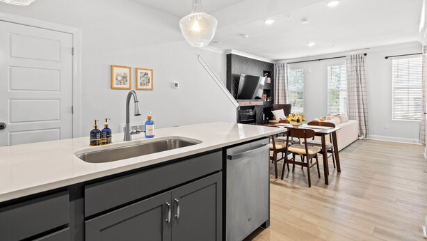 Une cuisine moderne dotée d’un grand îlot central, un coin repas avec une table et des chaises, et un espace de vie comprenant un canapé et un téléviseur.