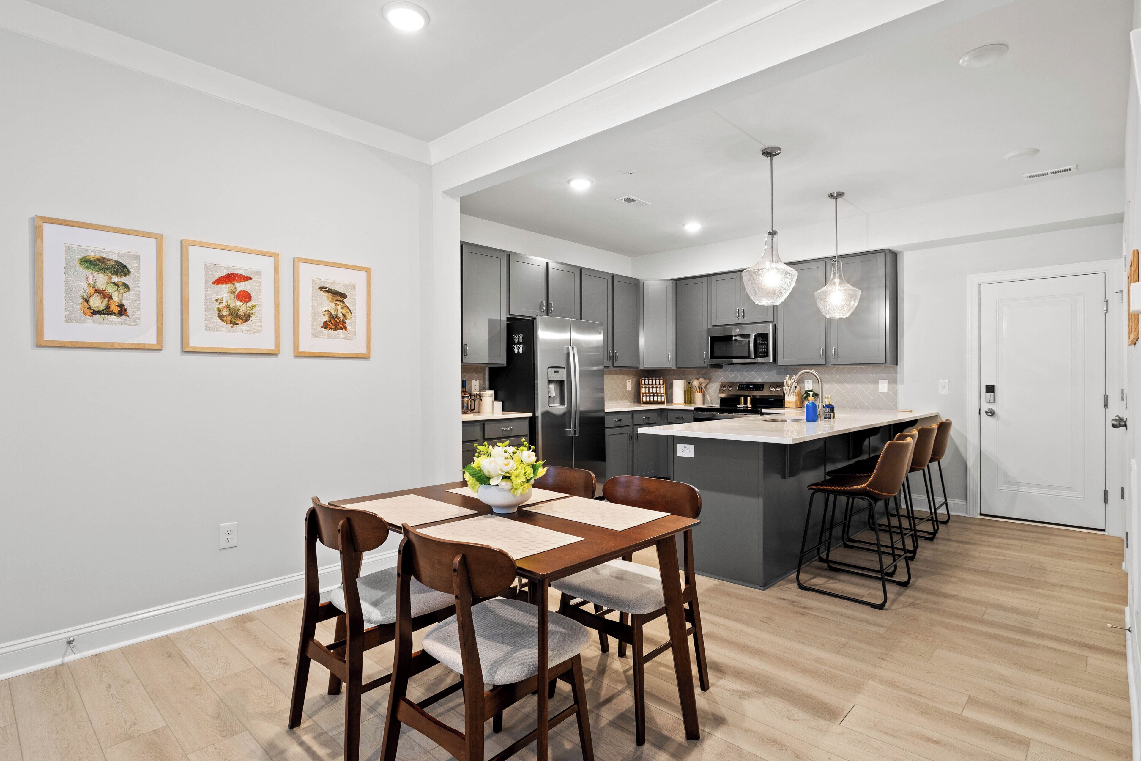 A modern kitchen with grey cabinets, stainless steel appliances, and a central island with bar stools.