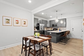 A modern kitchen with grey cabinets, stainless steel appliances, and a central island with bar stools.