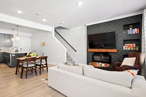 A modern living room with a sofa, a coffee table, and a TV mounted on a black wall.