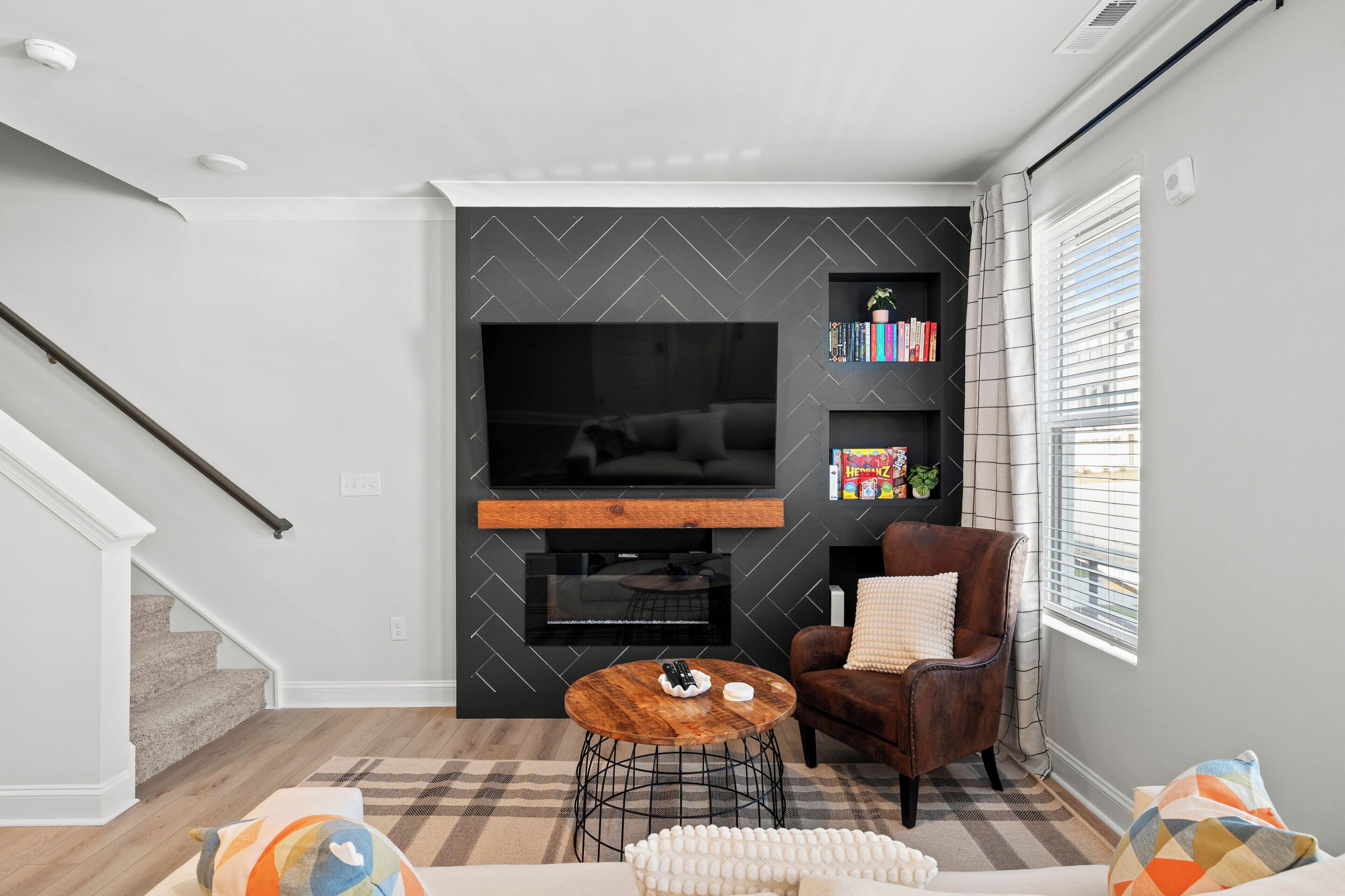 A modern living room with a fireplace, a flat-screen TV, a bookshelf, and a comfortable seating area.