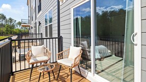 Une terrasse dotée de chaises en osier et d’une porte vitrée donnant sur un patio abrité.