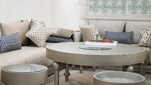 A round table with a tray of snacks, a sofa with patterned cushions, and a patterned wall. - Luxury apartment 160 m² - Fès Al Amal (fes)