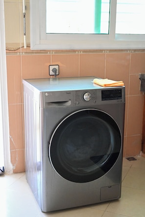 A compact, modern washing machine in a corner with a window above it. - Luxury apartment 160 m² - Fès Al Amal (fes)