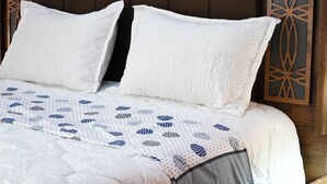 A bed with white pillows and a patterned bedspread, a wooden headboard, and a decorative panel on the wall. - Luxury apartment 160 m² - Fès Al Amal (fes)