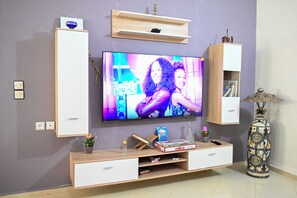 Ein modernes Wohnzimmer mit Flachbildfernseher, Holz-Unterhaltungseinheit und Dekorationselementen.