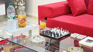 A glass-top table with a chessboard, a bottle of mango juice, a bottle of water, and a glass of orange juice. - Luxury apartment 160 m² - Fès Al Amal (fes)