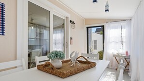 A dining area with a white table, wicker tray, white chairs, and a potted plant. - NEW Twin Tides Retreat-steps to private beach. Two Homes, One Memorable Stay (Clinton)