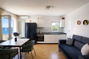 Eine kompakte Küche mit Essbereich, einer Couch und Meerblick.