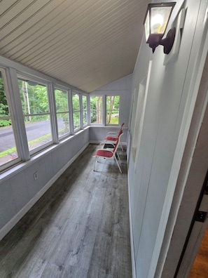 Una habitación con amplios ventanales, piso de madera y dos sillas rojas.