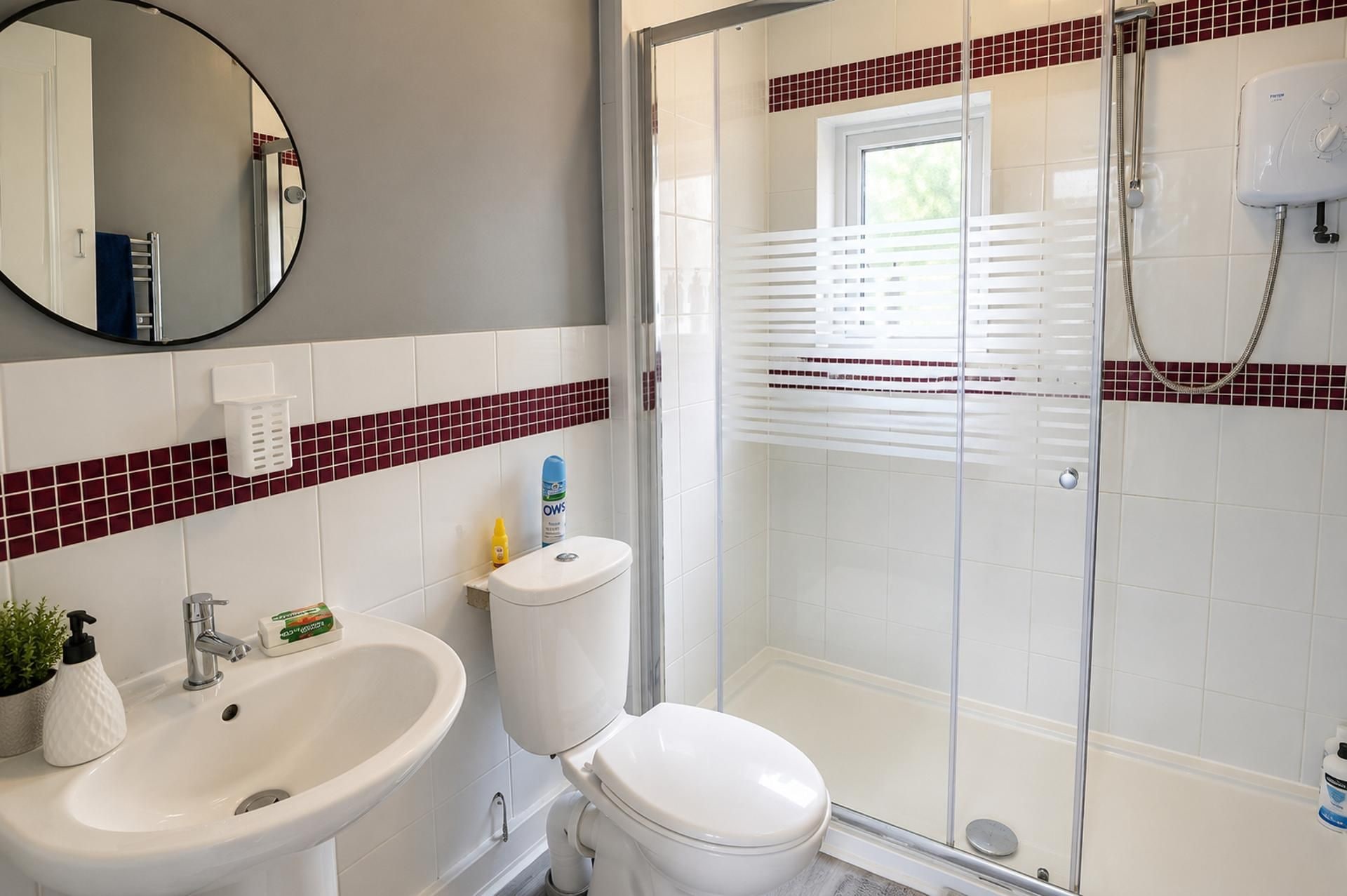 A bathroom with a white sink, toilet, and shower enclosure.