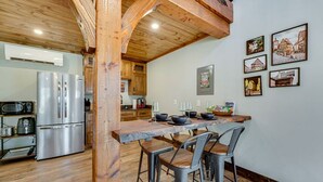 A kitchen with a wooden ceiling, stainless steel appliances, and a bar area with stools.