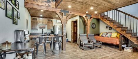 A spacious loft-style living area with a kitchen, dining area, and a staircase leading to an upper level.