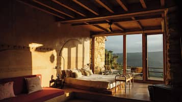 A bedroom with a large bed, a sofa, a table, and a fireplace.