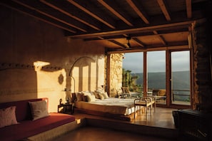 A bedroom with a large bed, a sofa, a table, and a fireplace.
