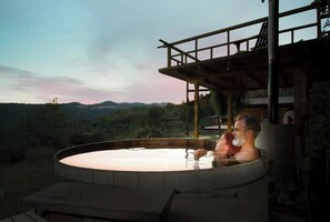 Un bain à remous avec vue sur les montagnes, une terrasse en bois et un espace couvert.