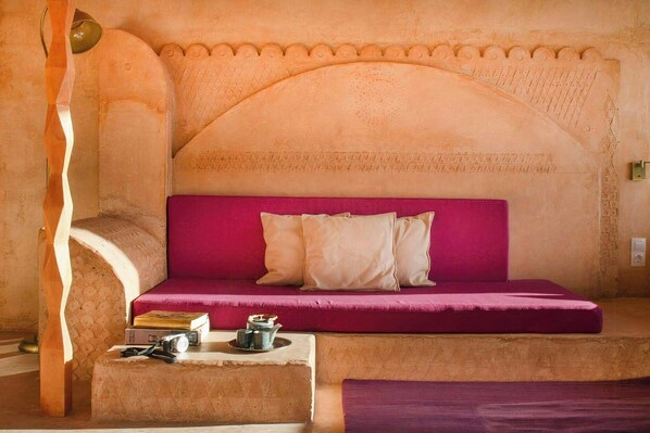 A room with a sofa bed, a small table with books and a camera, and a decorative wall with carved patterns. - Farmhouse with pool, bath and spectacular views (Villahermosa del Río)