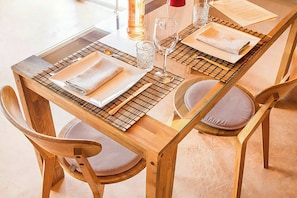 A wooden dining table with a glass top, surrounded by wooden chairs with cushioned seats. - Farmhouse with pool, bath and spectacular views (Villahermosa del Río)