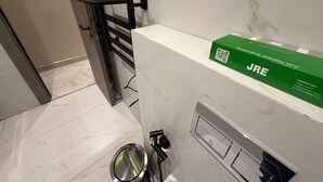 Een badkamer met een handdoekhouder, een groene doos met de tekst 'JRE' en een roestvrijstalen wastafel.