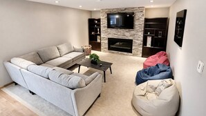Un salon comprenant un canapé, une table basse, une cheminée et un téléviseur fixé au mur.
