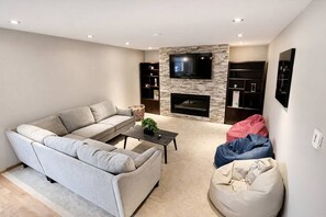 Ett vardagsrum med en soffa, ett soffbord, en öppen spis och en tv som är monterad på väggen.