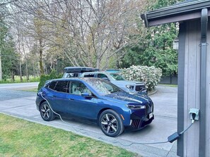 En blå bil parkerad på en uppfart bredvid en laddstation.