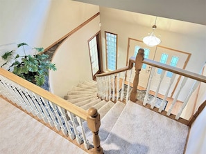 Eine Treppe mit Holzwangen und einem Chandelier, die zu einem Raum mit Ausblick führt.