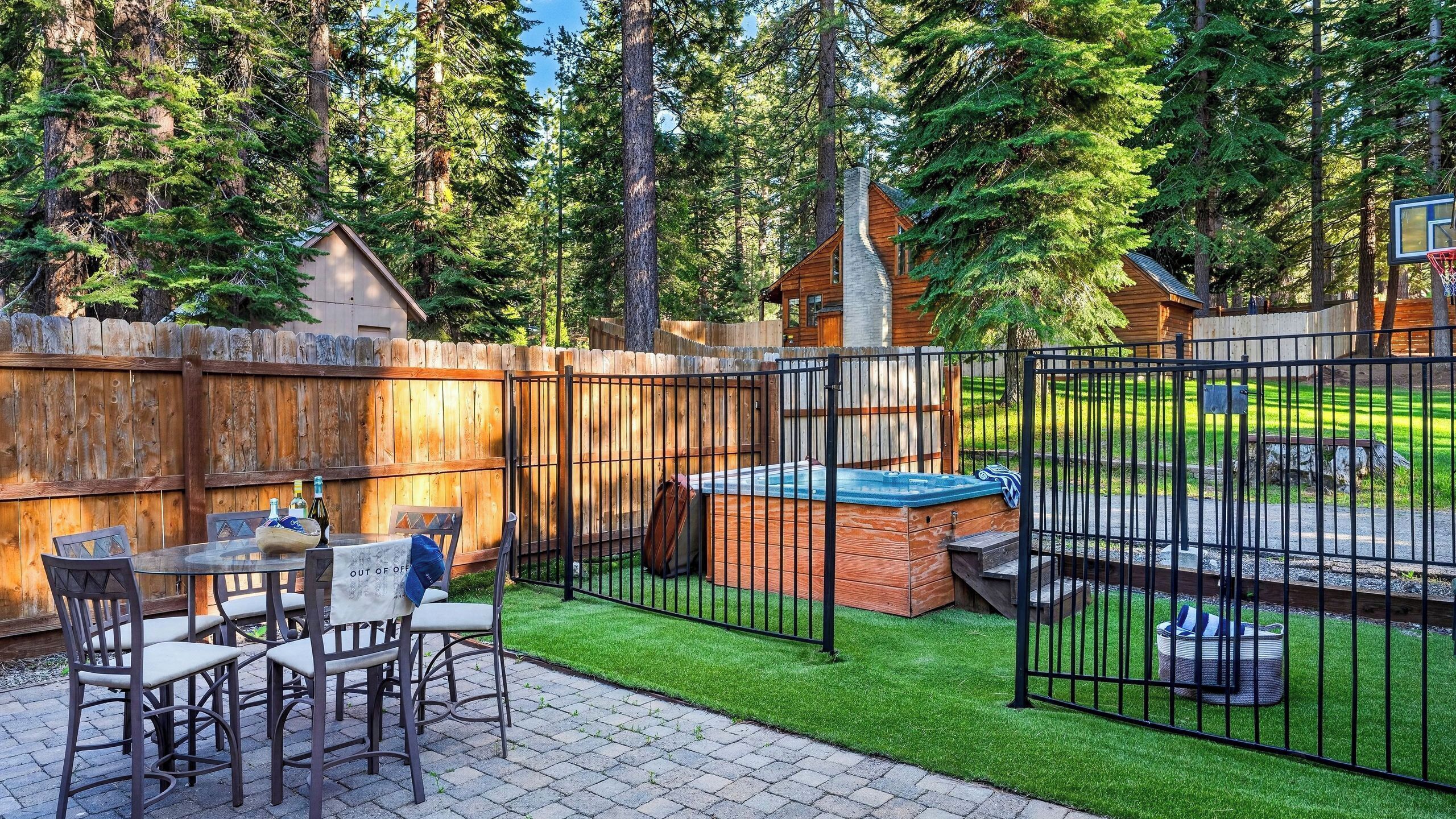 A backyard with a wooden fence, a hot tub, and a patio table with chairs.