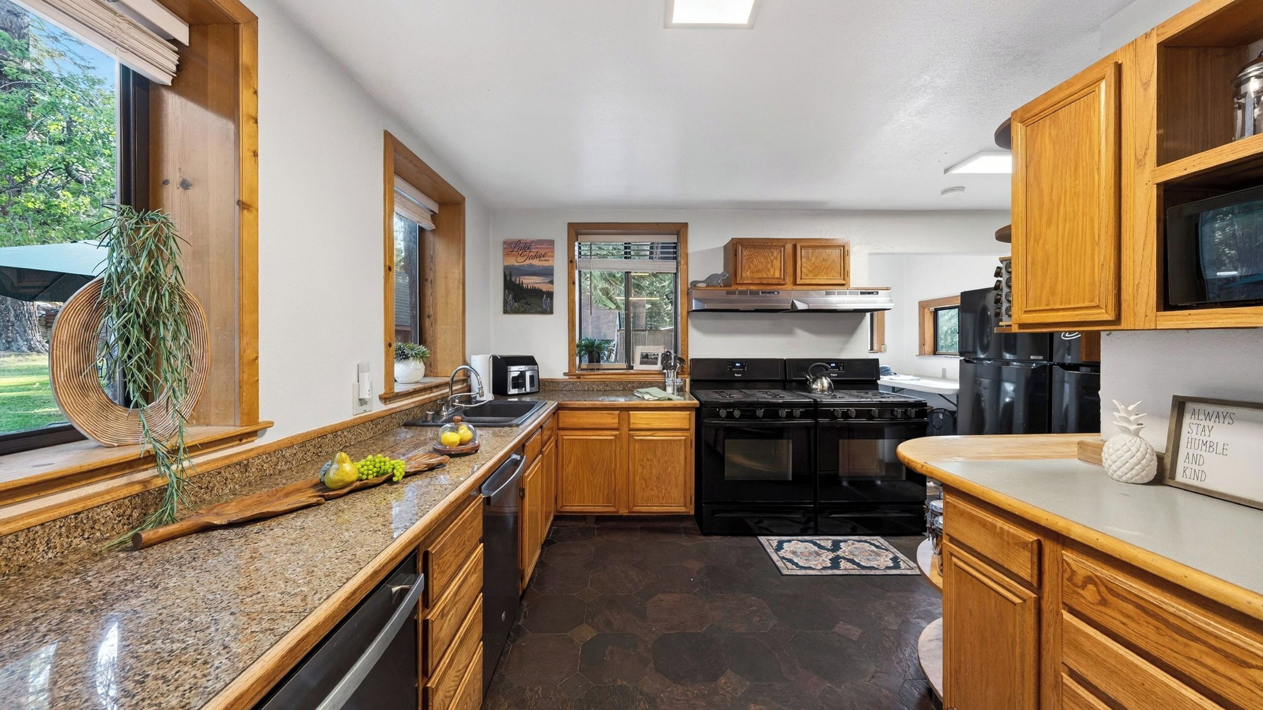 A kitchen with wooden cabinets, granite countertops, a stove, and a refrigerator.