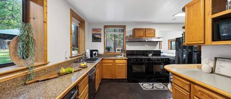 A kitchen with wooden cabinets, granite countertops, a stove, and a refrigerator.
