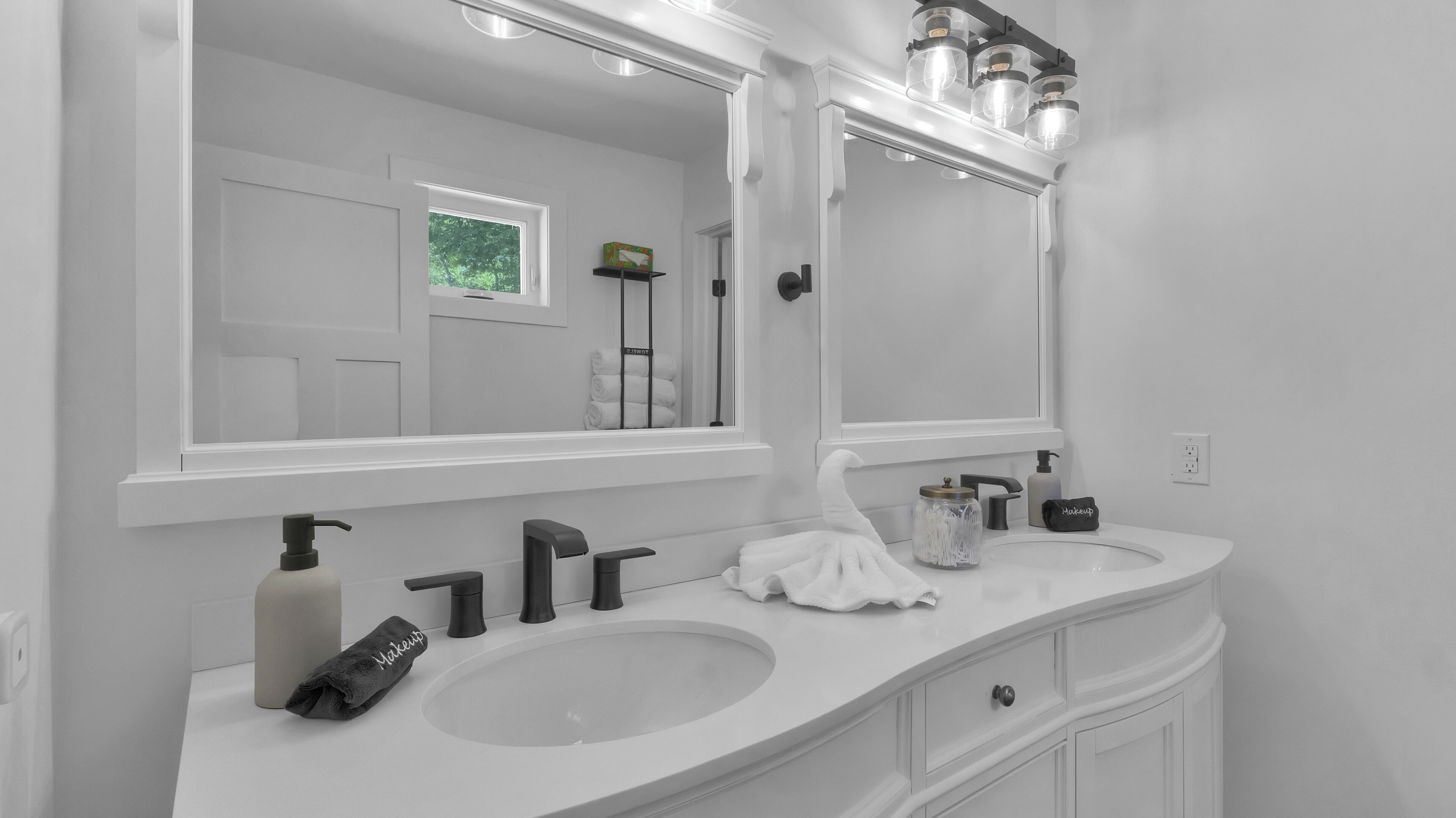 A bathroom with two sinks, a large mirror, and a towel rack.