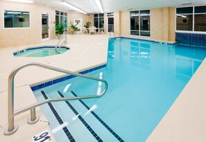 Une piscine intérieure avec des couloirs bien délimités, un poste de surveillance pour le sauveteur et un petit espace détente avec des chaises.