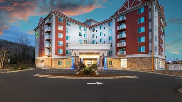 A multi-story hotel with a central entrance, multiple balconies, and a parking lot. - Cozy 1-bedroom, 2 queen bed, hotel suite with AC in soothing Downtown Ashville (Ashville)
