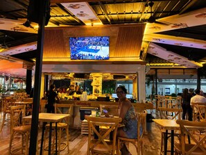 A restaurant with wooden furniture, a bar area, and a TV screen displaying a sports event. - Eco Avalon Paradise Villa (Punta Cana)