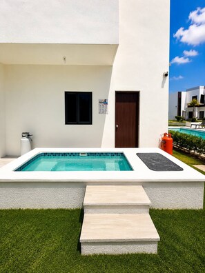 A modern building with a swimming pool, a door, and a small window. - Eco Avalon Paradise Villa (Punta Cana)