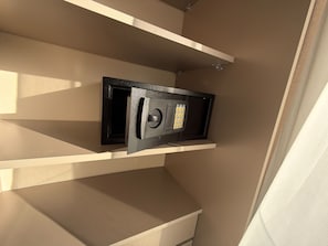 Una caja fuerte empotrada en la pared, pared color beige y estante blanco.