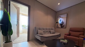 A modern living room with a grey sofa, a black coffee table, and a brown armchair. - 406 Tara-jre Jabal Al Lweibdeh With Stunning View (Amman)