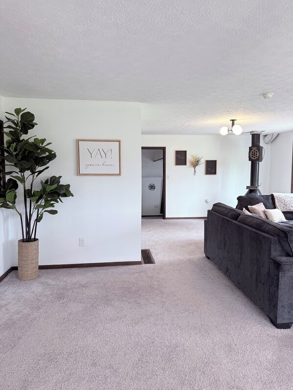 A living room with a dark sofa, a large plant, and a framed quote on the wall.