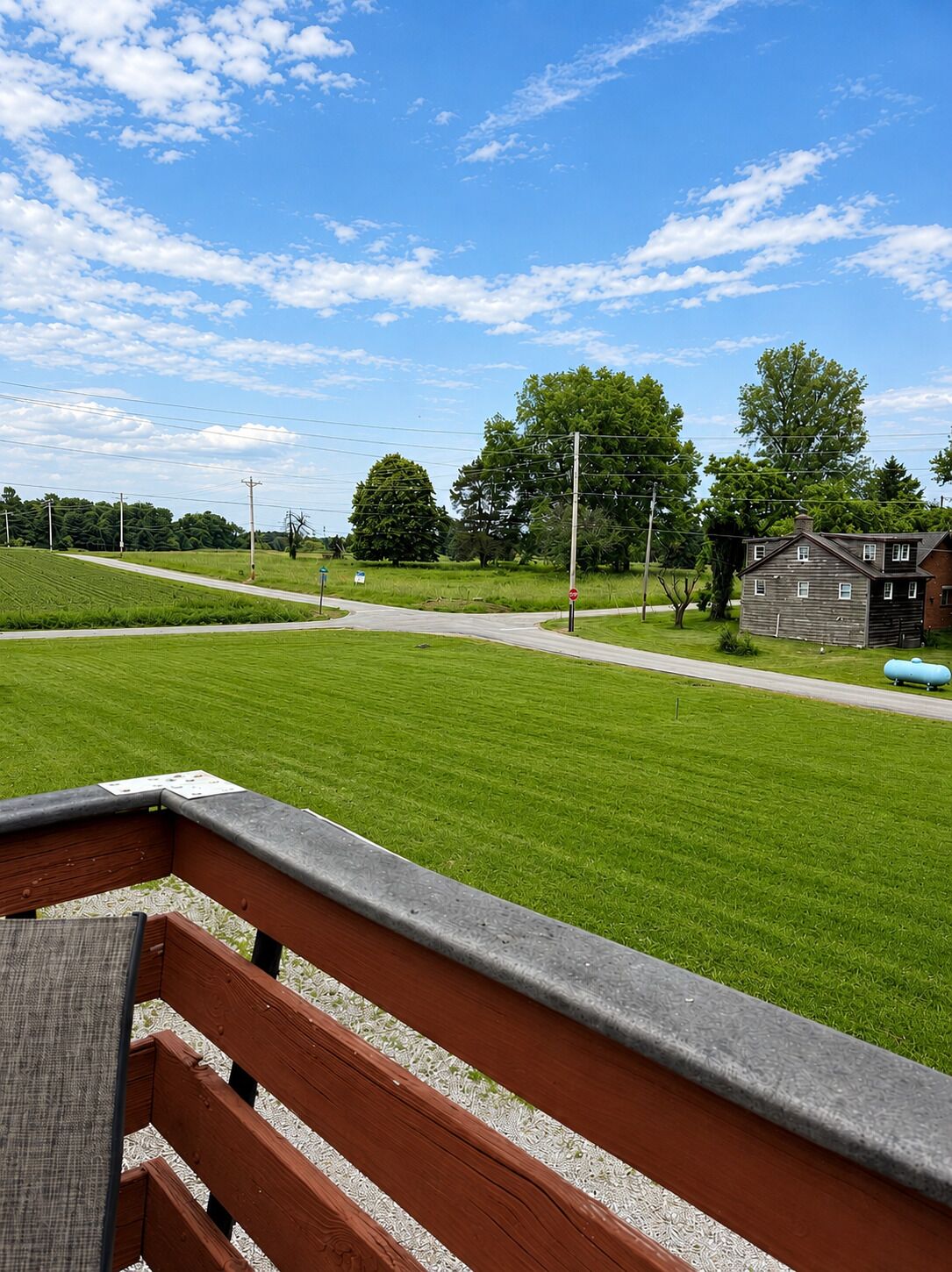 A grassy field with a bench, a building, and a clear sky.