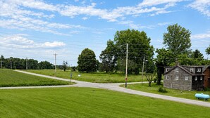 Un champ verdoyant avec un banc, un bâtiment et un ciel dégagé.