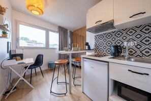 Een compacte keuken met een eethoek, een kleine koelkast en een raam met uitzicht.