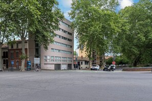 Een meerlaags gebouw in moderne bouwstijl, een straat met een verboden toegangsbord, en een fietser op de voorgrond.