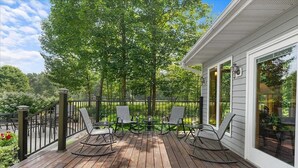 Une terrasse en bois avec des sièges extérieurs et une vue sur une zone boisée.