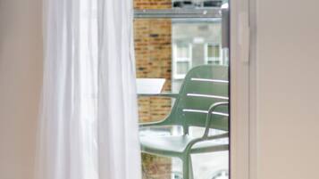 A balcony with a glass door, a brick wall, and a green chair.